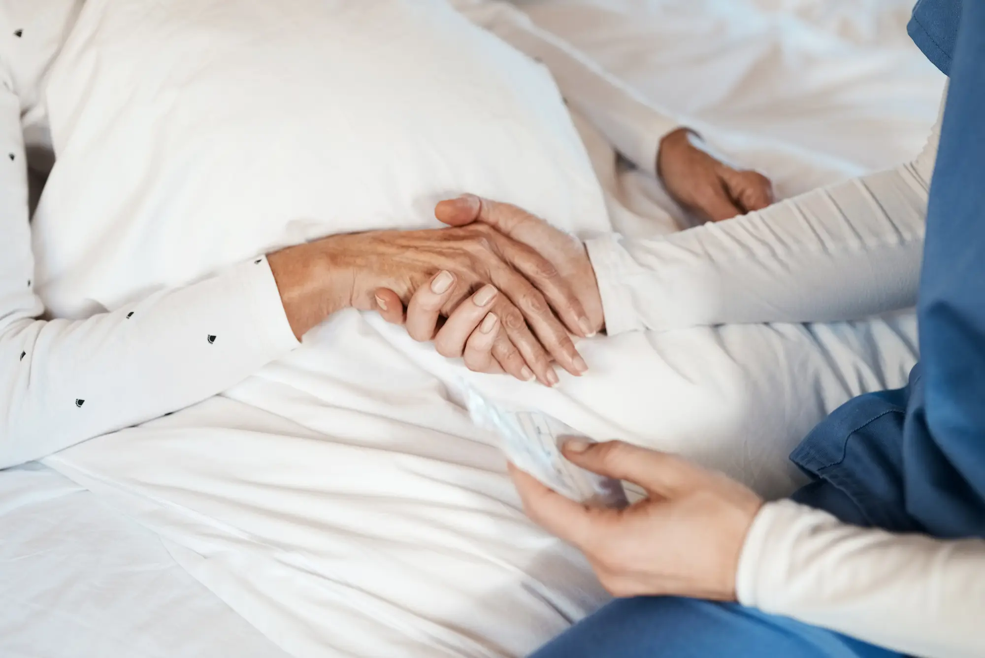 Pflegekraft hält liebevoll die Hand einer bettlägerigen Patientin – individuelle 1-1 Intensivpflege in der häuslichen Umgebung durch starMed