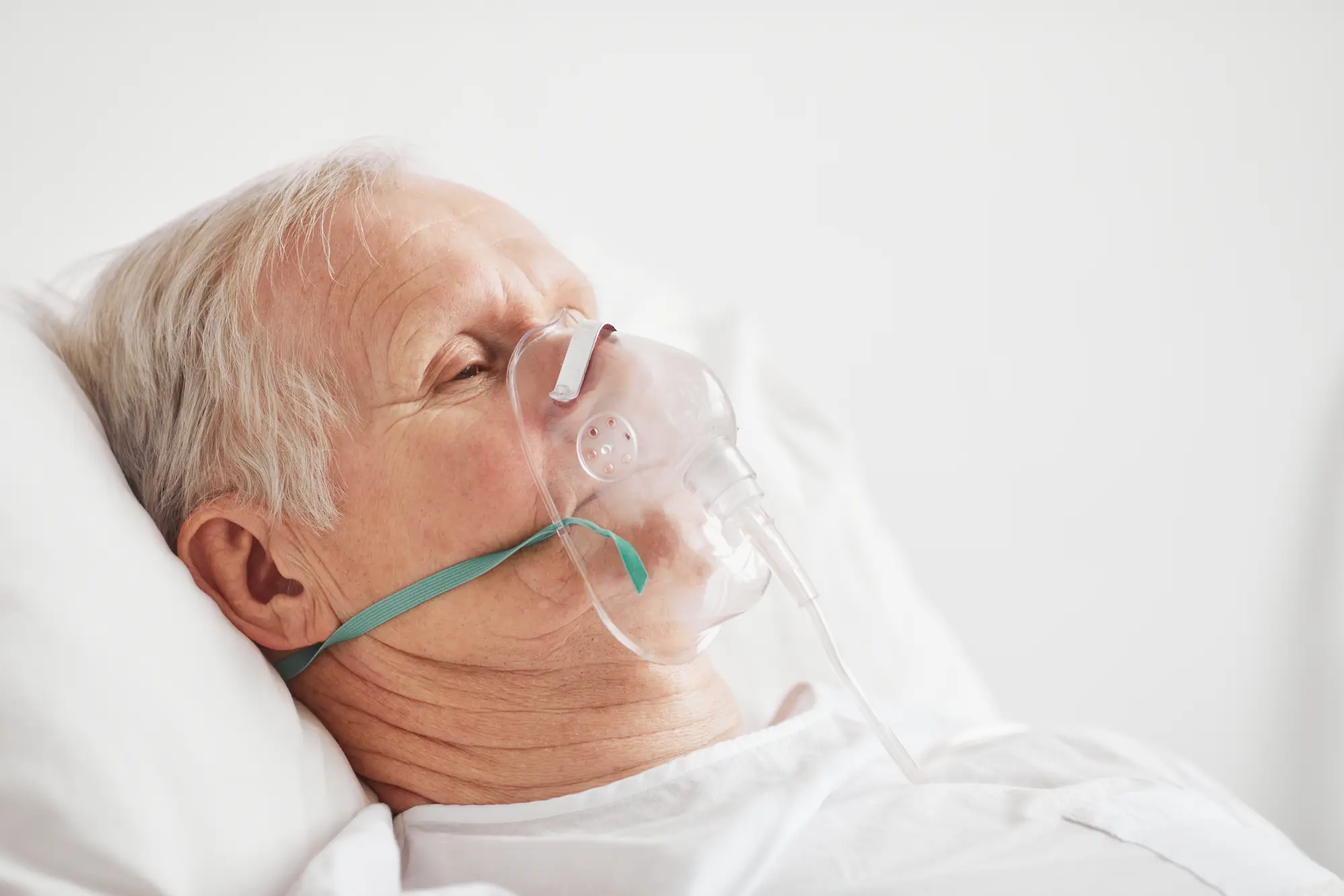 Älterer Patient mit Sauerstoffmaske liegt im Bett – außerklinische Beatmung im Rahmen der 1-1 Intensivpflege zu Hause durch starMed.
